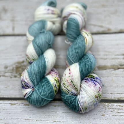 Two bluish green and white colored skeins of yarn.