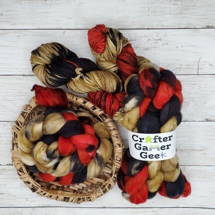 Two skeins of yarn and two braids of fiber containing shades of tan, red, and black.