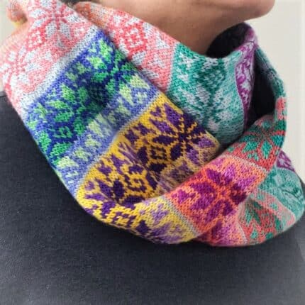A multi-colored fair isle star pattern infinity cowl wrapped around a person's neck.