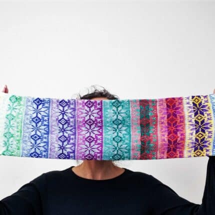 A person with extended arms holding a multi-colored fair isle star pattern infinity cowl.