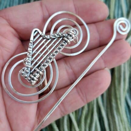 A silver metal harp shawl pin.