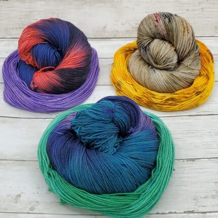 Coiled keins of blue and orange, brown speckled and blue and purple yarn nested within lavender, yellow and sea green mini hanks.