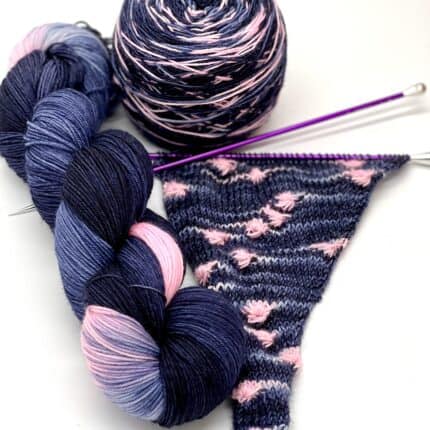 A navy and pink skein of yarn, and the beginnings of a shawl to show how it knots with assigned pooling.