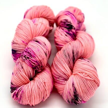 Two coral pink skeins of yarn with neon pink speckles.