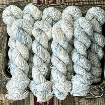 Several skeins of porcelein color yarn with Copenhagen blue speckles.