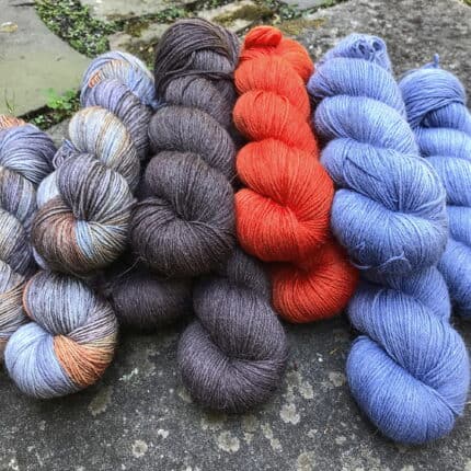 Skeins of solid Cornflower blue, tomato red and soft borwn and several skeins of a variegated yarn in matching colors.