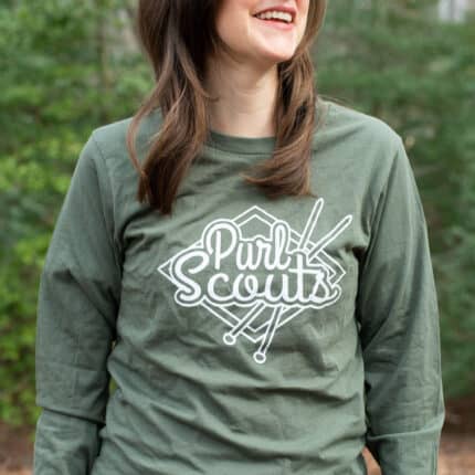 An olive green long sleeve Purl Scouts t-shirt, worn by a light-skinned model.