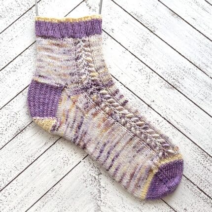 A speckled purple and yellow knitted sock.