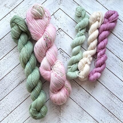 Skeins of green, pink, white and purple yarn.