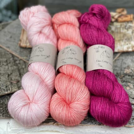 Three skeins of yarn in different shades of pink.
