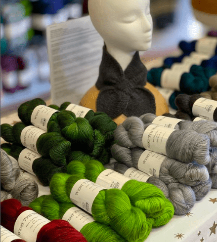 Red, green and gray yarn arranged on a table.