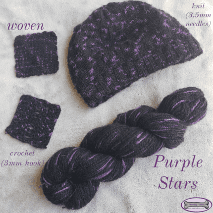 A mostly black skein of yarn with purple spots on a grey background. Around the skein are a small crochet sample, a small woven sample and a knit hat.