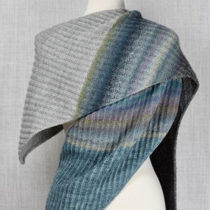 A gray and blue ribbed shawl on a dress form.