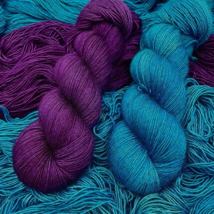 Skeins of cobalt and red-violet yarn laid on unfurled skeins of the same colors.