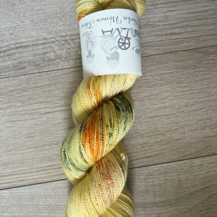 A skein of yellow yarn with green, purple and orange speckles.