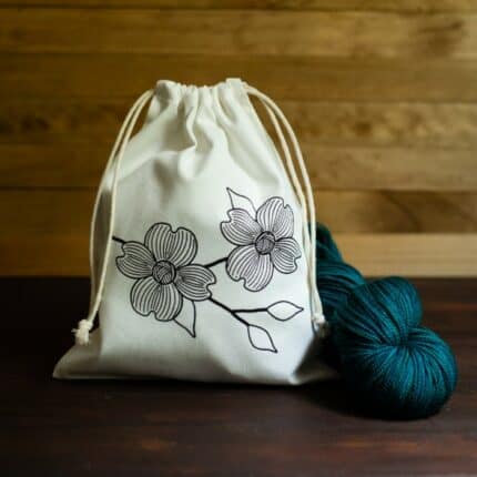A drawstring bag with a dogwood branch screen printed on the front.
