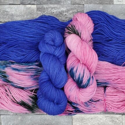Pink variegated skeins containing deep blue and green accents, beside semisolid purple skeins.