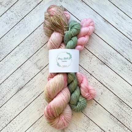 A skein of yarn in pink with two mini skeins in green and pink.