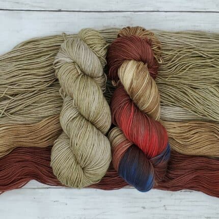 Hand painted skeins containing various shades of brown, tan, red, and blue beside semisolid taupe skeins.
