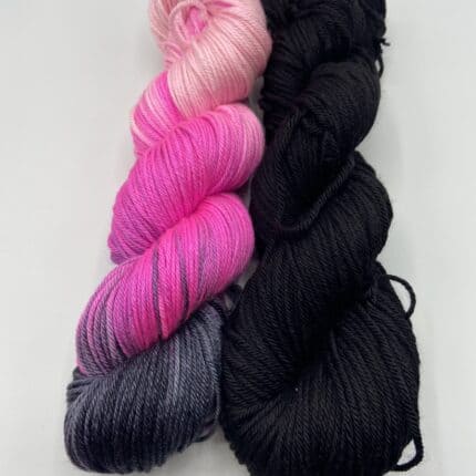 A skein of variegated pink yarn and a skein of black yarn.