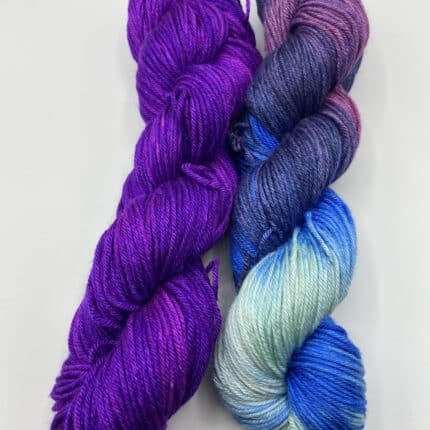 A skein of blue variegated yarn and a skein of purple yarn.