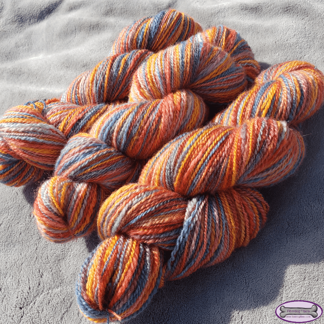 Three skeins of yarn in a mix of orange, pink, red and blue colors.