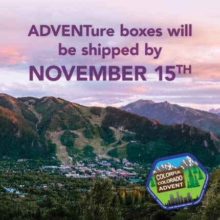 A mountain landscape overlooking a town in a valley with the text Adventure boxes will be shipped by November 15th on top of the skyline.