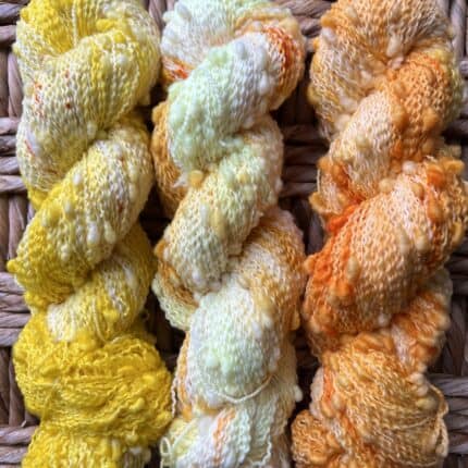 Skeins of yellow and white and orange and white yarn with slubs.