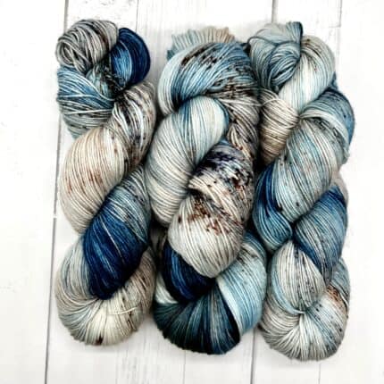 Blue and white skeins of yarn with grey and brown speckles.