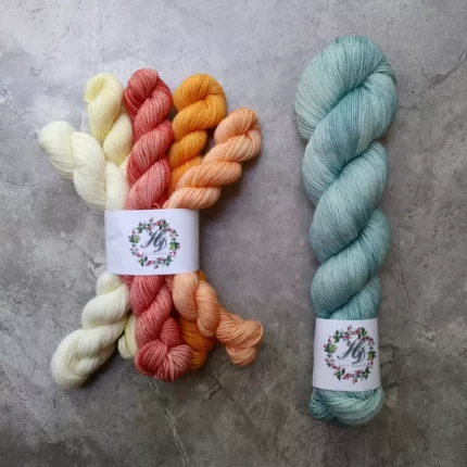 A yellow, peach and rose mini skein set and a full skein of light teal sock yarn.