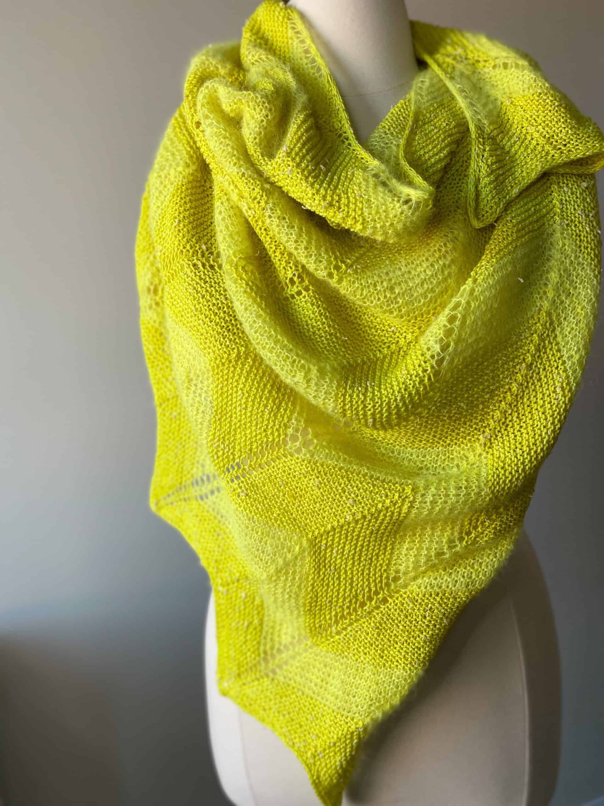 Bright lemon yellow shawl draped around mannequin showing off garter and chevron stitches with fingering and suri yarn.