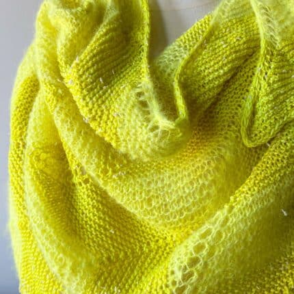 Close-up to show off texture of fingering and suri yarn in bright lemon yellow knit in garter and chevron stitches.