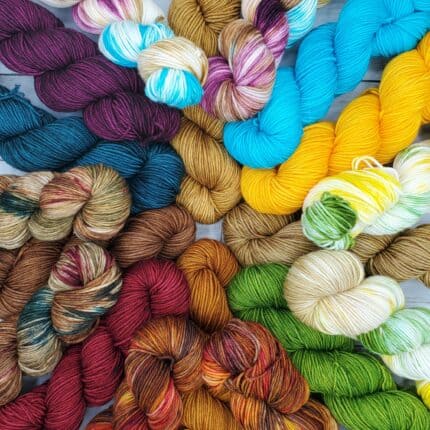 A pile of variegated and semisolid skeins of yarn in a variety of colors.