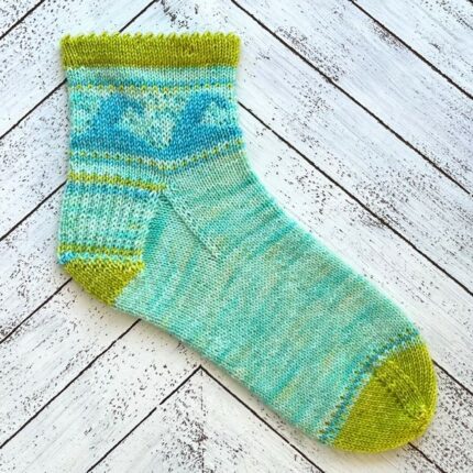 A knit sock with waves in blue and green.