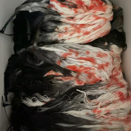 Loose skeins of black, white and orange yarn.
