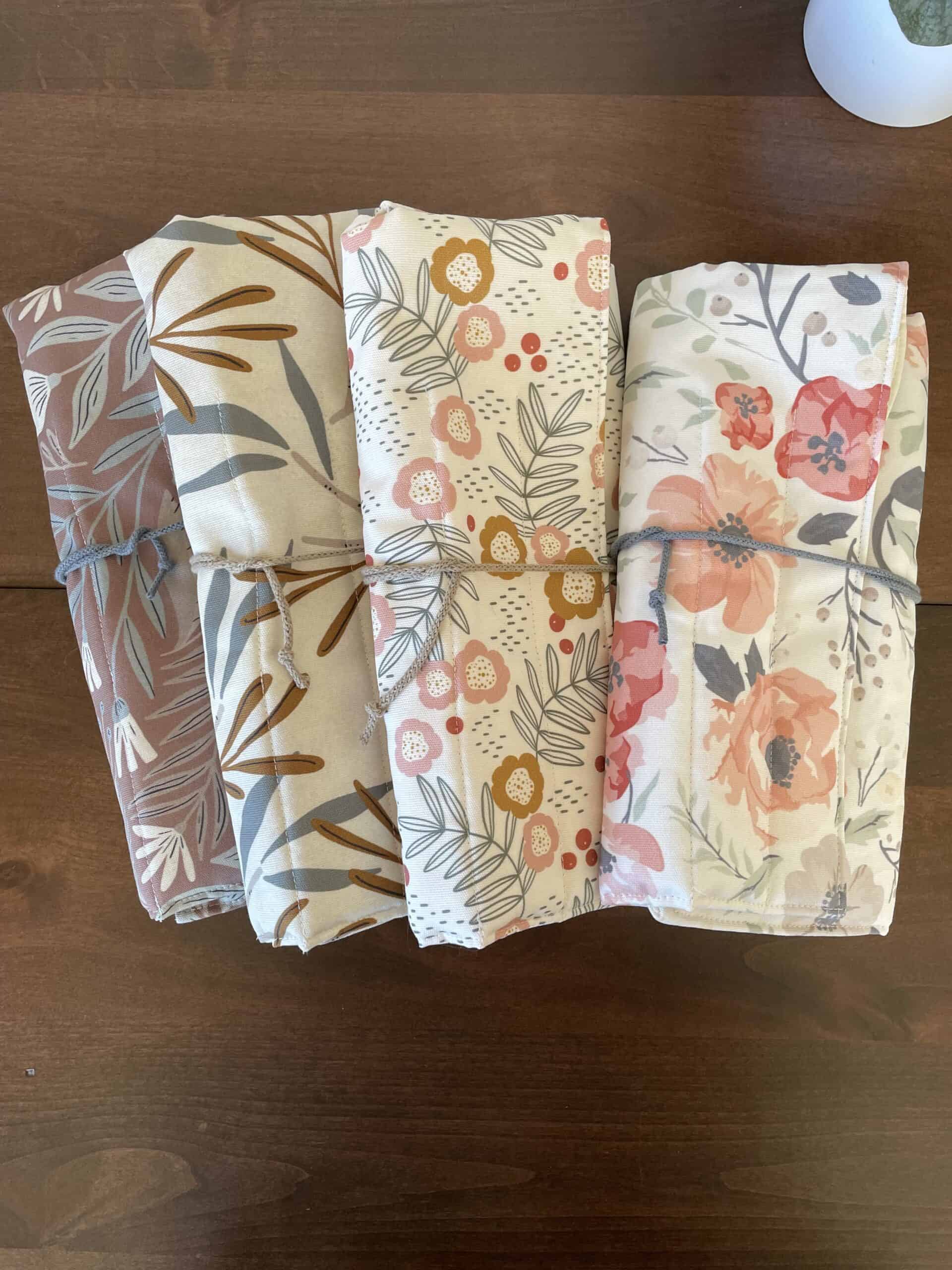 A collection of four folded needle roll cases in a variety of floral prints.