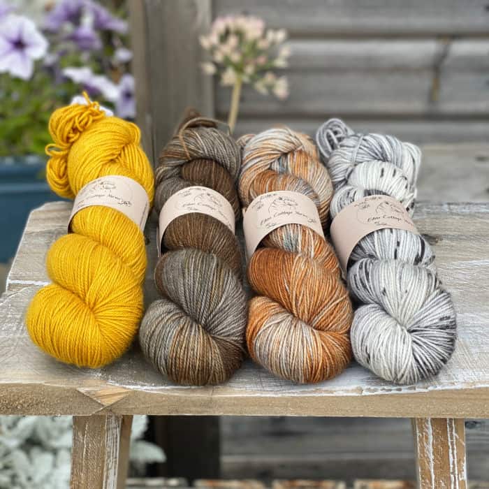 Four skeins of yarn in shades of brown and yellow.