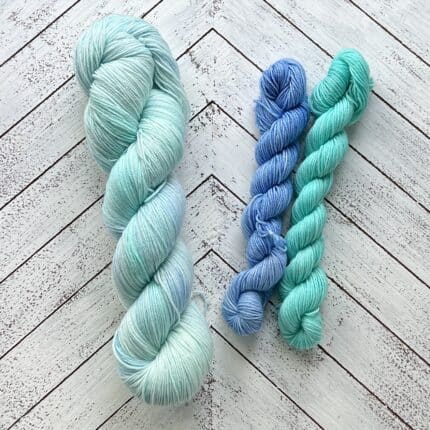 One large skein of yarn in light aqua and two small skeins of yarn in blue and aqua.