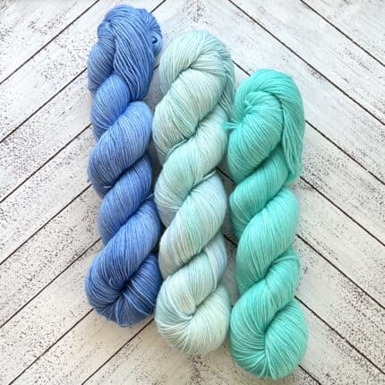 Three skeins of yarn in blue, pale blue, and aqua.