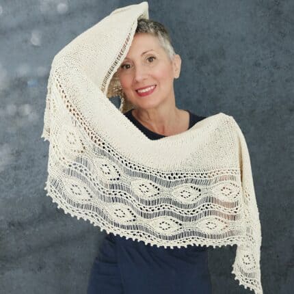 A white woman wearing a shawl. The shawl has a half donut shape and a lacy border.