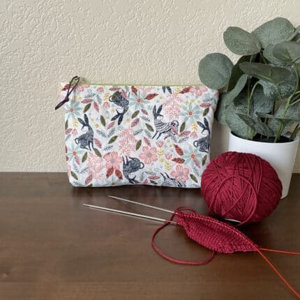 A quilted zipper pouch featuring a patterned fabric with rabbits in sweaters.