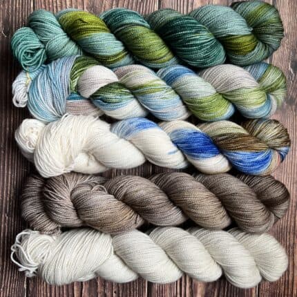 White,grey, and green skeins with various variegated skeins of blue and greens.