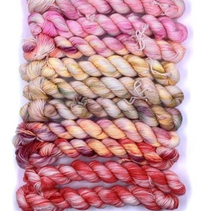 A set of gradient yarn in pink to orange to red.