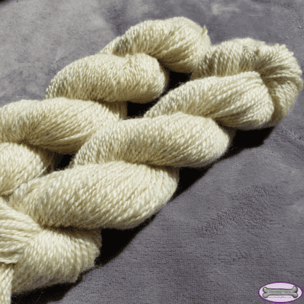 Two ivory skeins of yarn on a grey background.