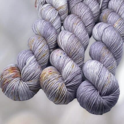 Three skeins of lavender yarn with speckles.