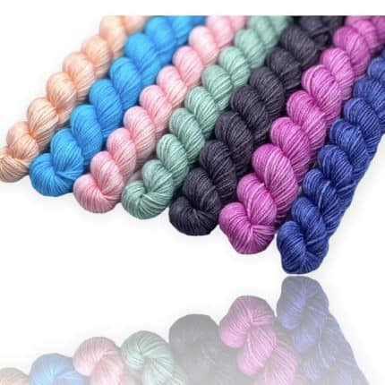 A set of seven solid color mini skeins of yarn in blues, pinks, green and gray.