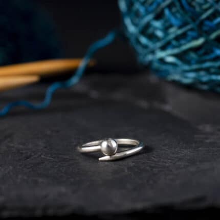 A silver ring in the shape of a knitting needle.