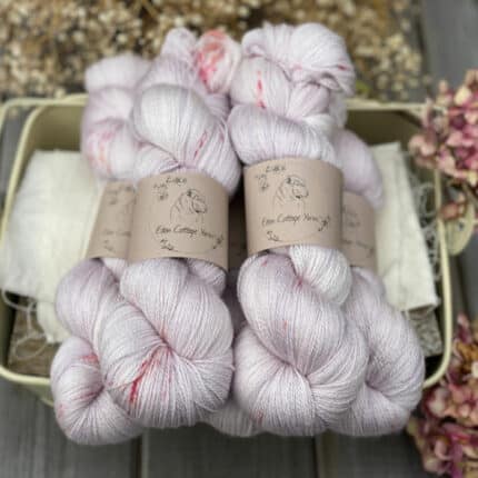 Five pale pink skeins of yarn with bright pink splashes.