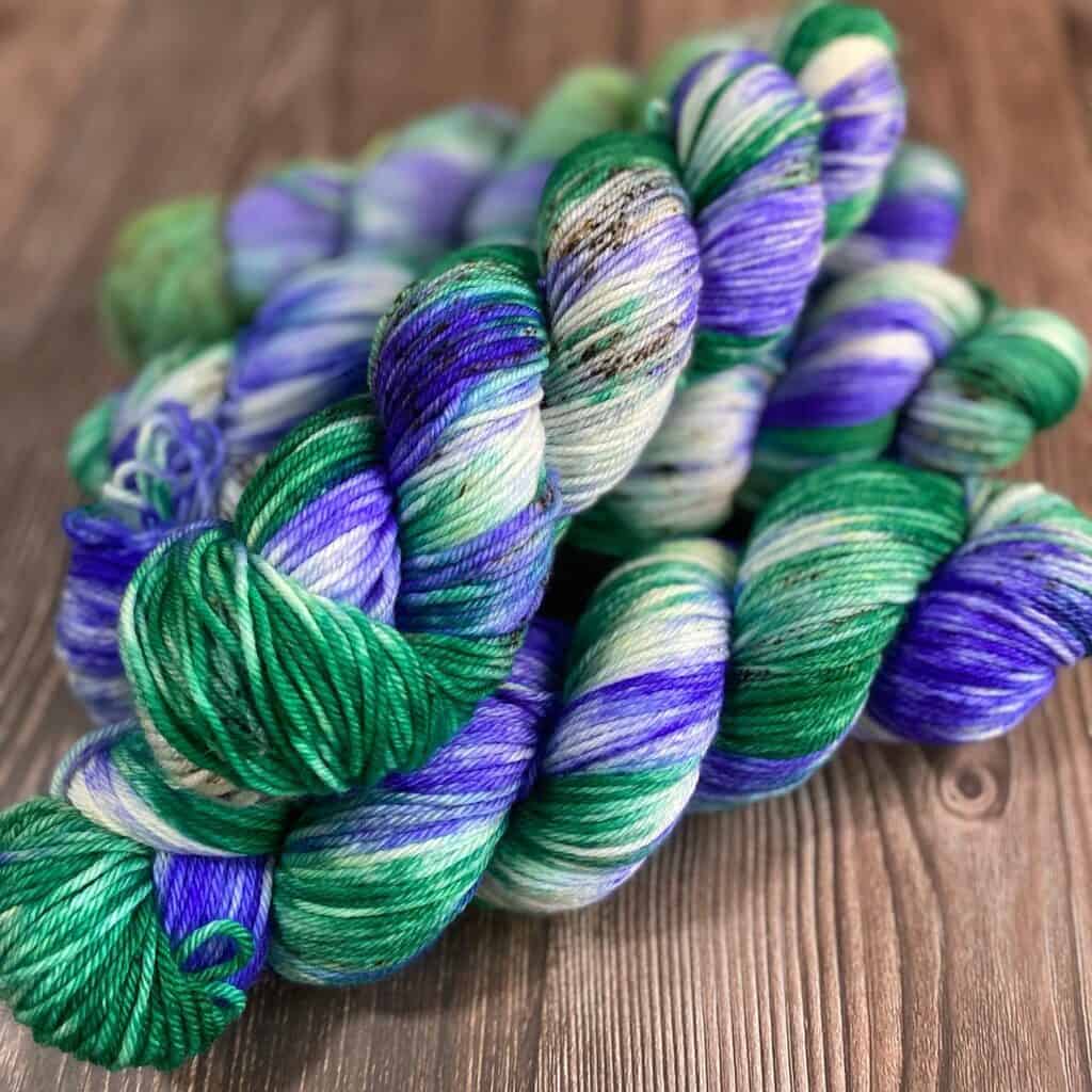 Skeins of yarn in green, purple and black speckles.