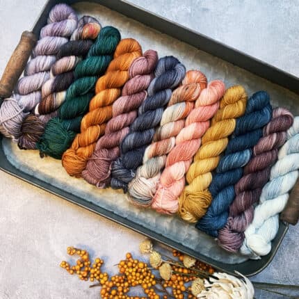 A set of 12 mini skeins of yarn in multiple colors.